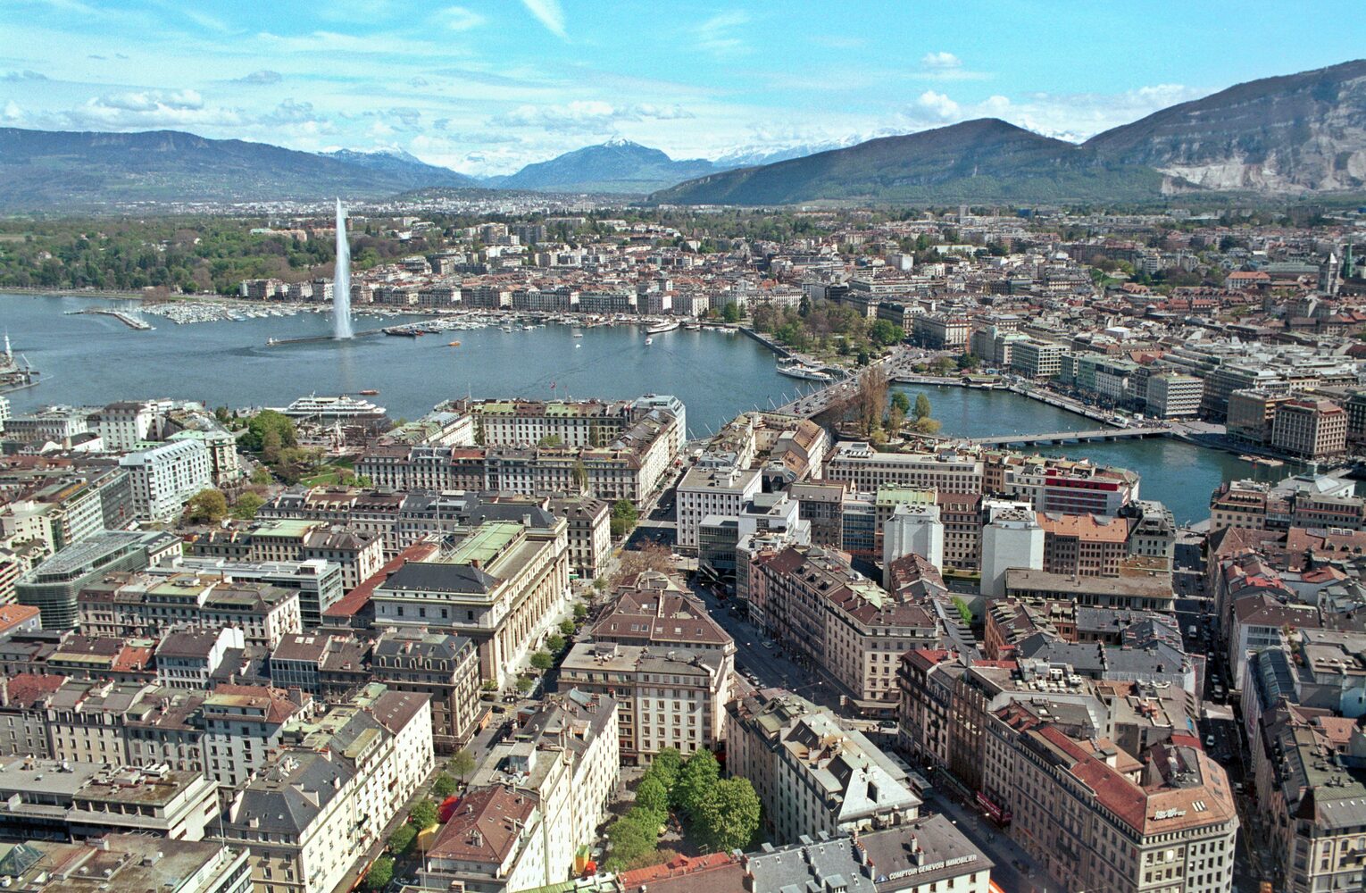 The Jet d'Eau fountain shooting water over Lake Geneva with the Alps in the background
