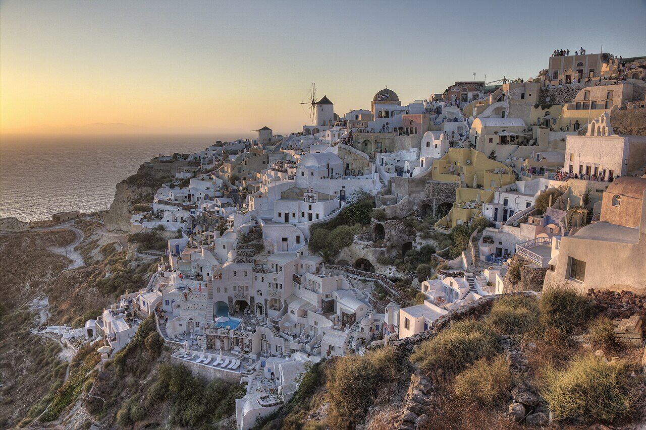 Iconic blue-domed churches and whitewashed buildings in Oia village overlooking Santorini's volcanic caldera